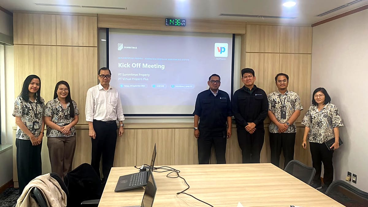 Tujuh orang berdiri di depan layar proyektor bertuliskan Kick Off Meeting PT Summitmas Property dan PT Virtual Properti Plus di ruang rapat berpanel kayu.